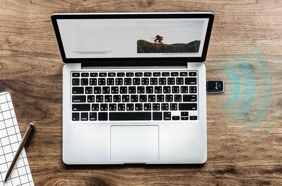 Zwarte TP-Link Archer T3U WiFi-adapter aangesloten op een open laptop, met wifi-signalen die uitstralen.