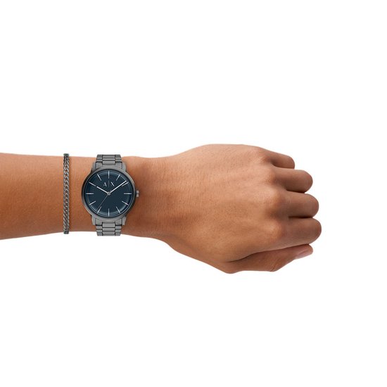Grijs Armani Exchange horloge en armband gedragen om de pols, met een blauwe wijzerplaat en A|X logo.