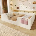 Laag kinderbed van lichtbeige teddy stof met roze opbergvakjes, opgemaakt met beddengoed.