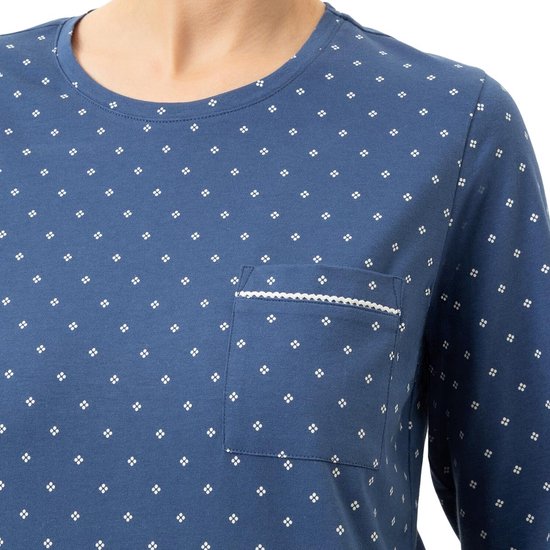 Dichtbij op het blauwe pyjamashirt met all-over witte stippen en een borstzak met witte bies.