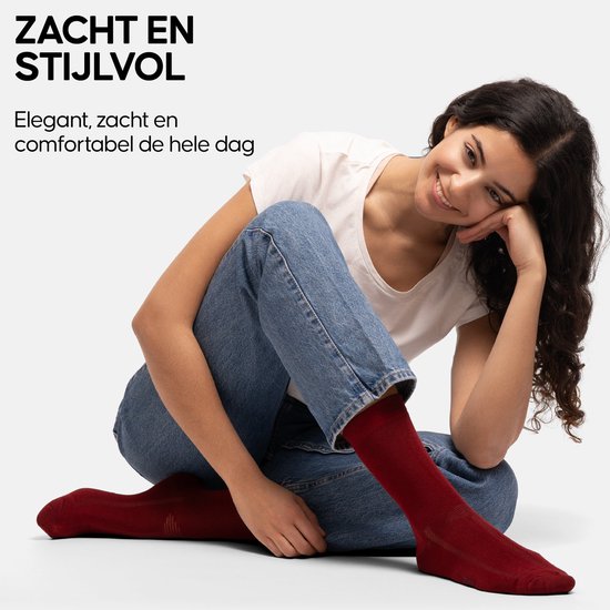 Model in spijkerbroek en witte top met een rode sok aan. Tekst 'ZACHT EN STIJLVOL'.