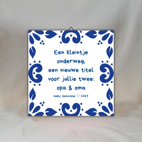 Carreau bleu de Delft avec le texte 'Un petit est en route, un nouveau titre pour vous deux : papi & mamie', avec le nom 'baby Genovese' et l'année '2027'.