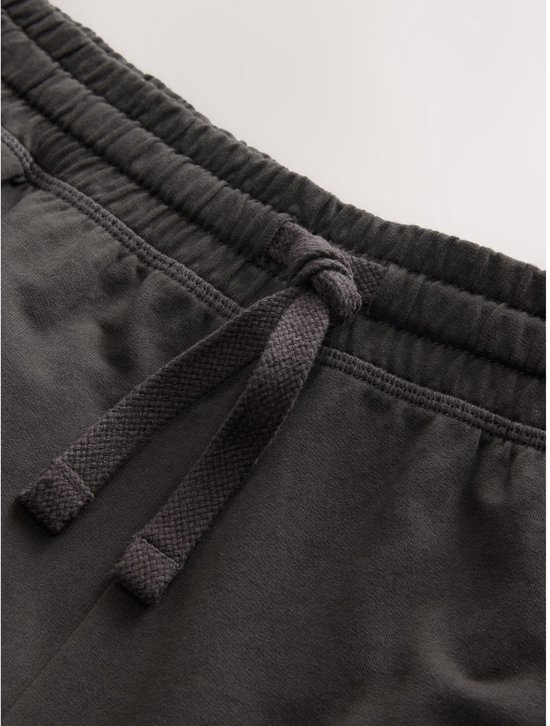 Close-up van de tailleband en het trekkoord van een donkergrijze joggingbroek.