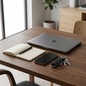 Bruine leren sleutelhanger met sleutels op een houten bureau naast een laptop, telefoon en notitieboek.