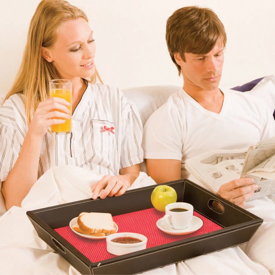 Man en vrouw in bed met ontbijt op bed. Rode placemat onder de mok, kom en appel.