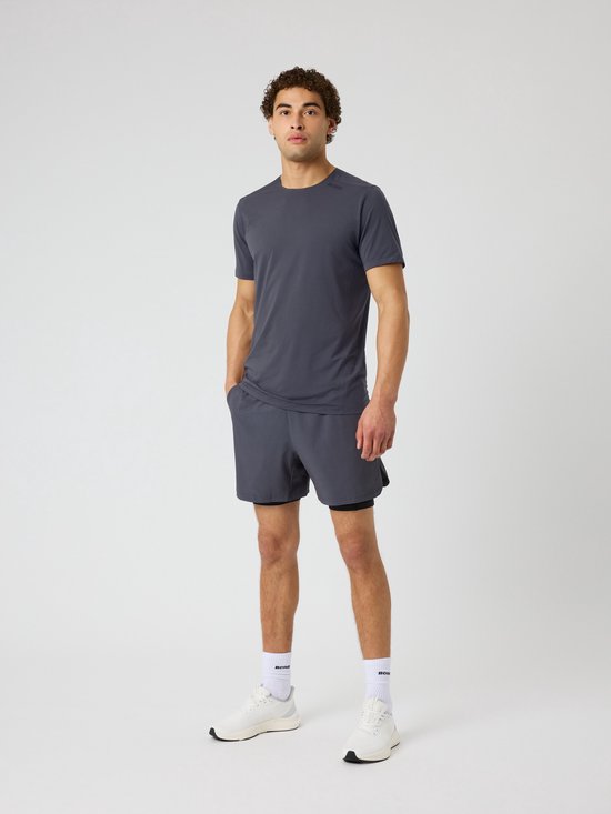 Model in een donkergrijs trainingspak: t-shirt en short met tight eronder.