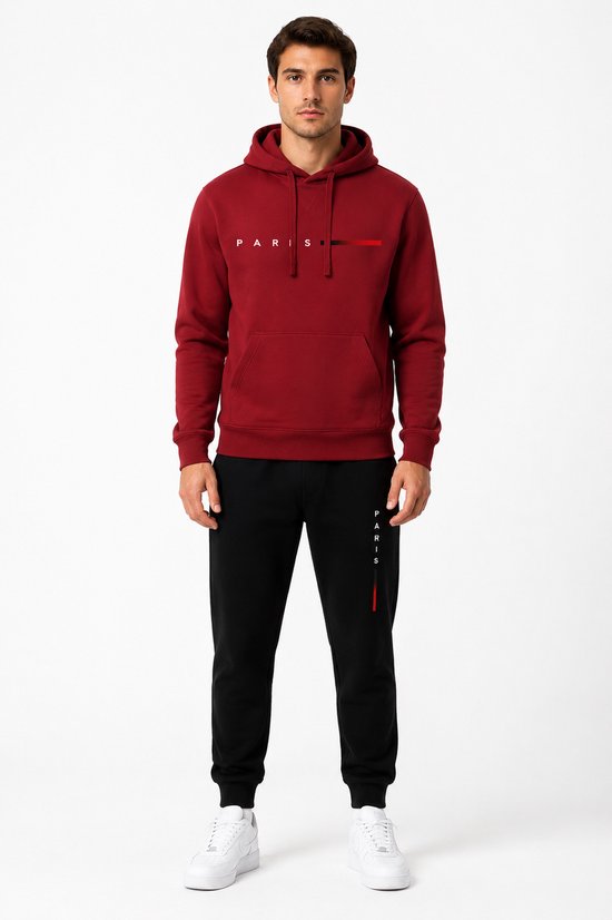 Man staand in bordeauxrode hoodie met 'PARIS'-print en zwarte joggingbroek met 'PARIS'-print.