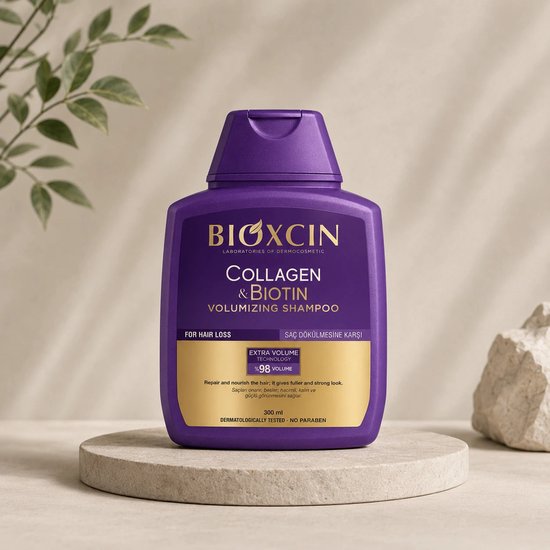 Paarse Bioxcin Collageen & Biotine Volume Shampoo fles met gouden label, op een betonnen display.