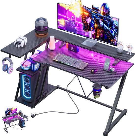 Zwart L-vormig gamingbureau met koolstofvezeltextuur, monitorstandaard, paarse LED-verlichting en gaming-accessoires.