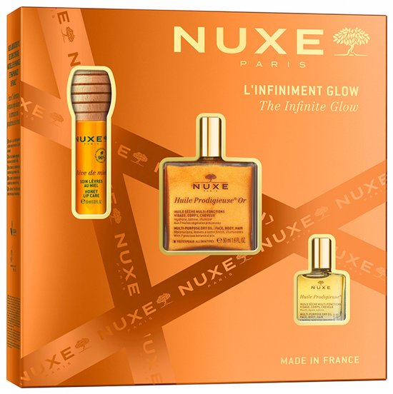 Coffret "L'Infini Glow" Nuxe sur fond orange, présenté avec trois flacons dorés : baume à lèvres, huile visage/corps/cheveux et une version miniature.
