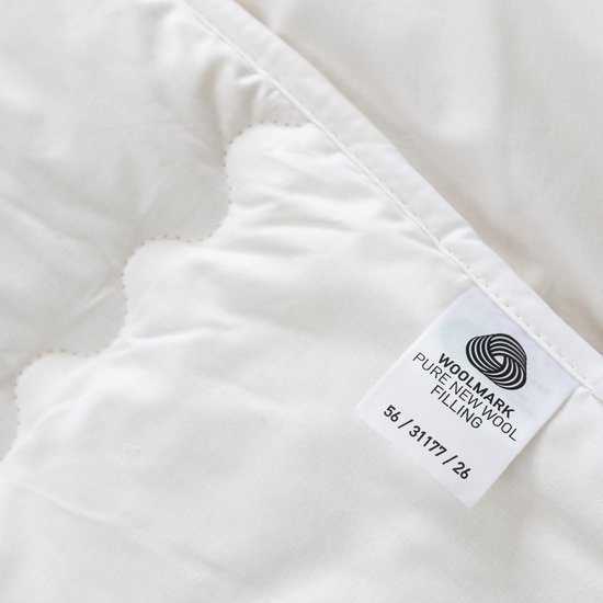 Witte wollen dekbed met een Woolmark label 'Pure New Wool Filling'.