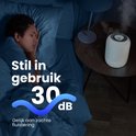 Humidificateur Auraonic blanc avec 30 dB de bruit. Une femme dort à côté.