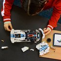 Van bovenaf gezien bouwt een meisje aan de witte LEGO Technic Dodge Viper GTS-R met blauwe strepen, op een tafel.