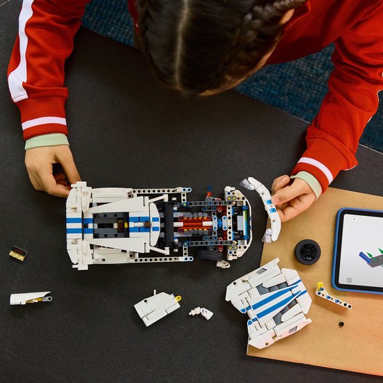 Van bovenaf gezien bouwt een meisje aan de witte LEGO Technic Dodge Viper GTS-R met blauwe strepen, op een tafel.