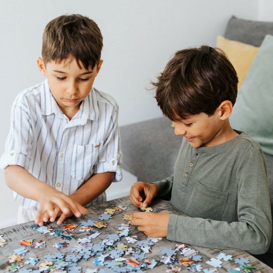 Twee jongens maken een puzzel op een tafel.