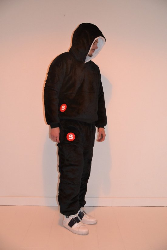 Zwarte oversized hoodie en joggingbroek met rode 'S' logo's. Model draagt witte sneakers.