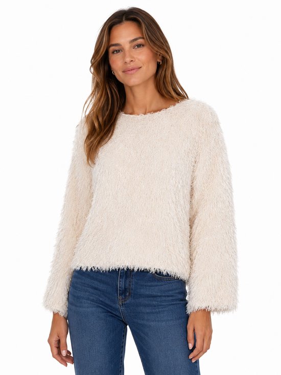 Model met een crème pluizige trui met lange mouwen en ronde hals, gecombineerd met een spijkerbroek.