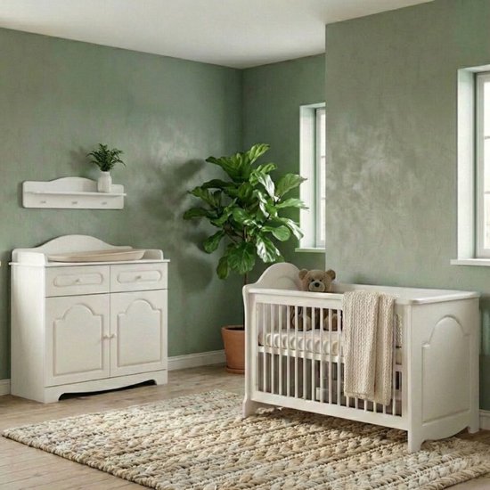 Witte babykamer met ledikant, commode met luiertafel, planten en een beige vloerkleed in een kamer met groen behang.