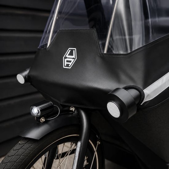 Zwarte voorzijde van een bakfiets met een doorzichtige kap, een wit logo en twee koplampen.