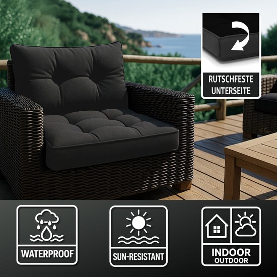 Donkergrijze rotan fauteuil met dik zwart kussen op een houten terras. Iconen geven aan dat het kussen waterdicht, zonbestendig en voor binnen/buiten is.