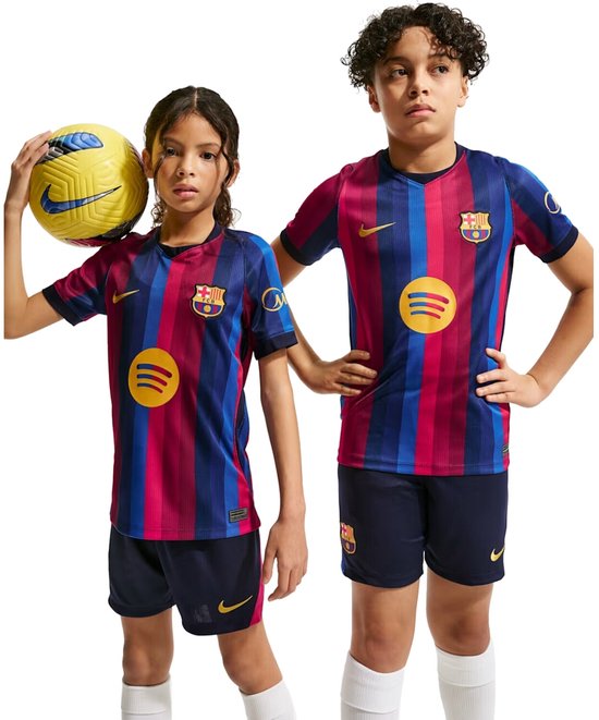 Twee kinderen in Barcelona voetbalshirts met roze en blauwe strepen, de jongen rechts draagt ook een bijpassend broekje.