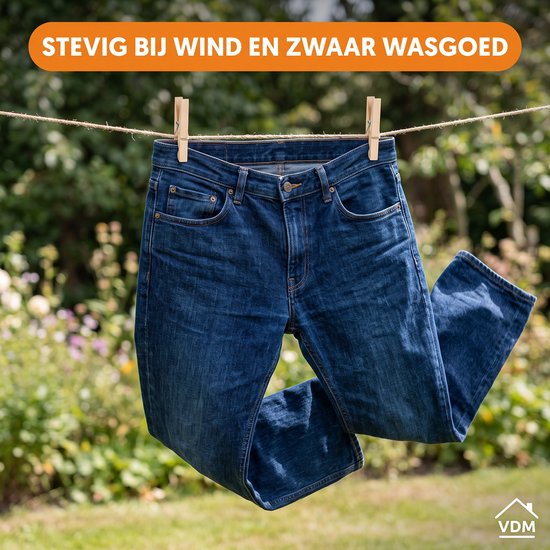 Donkere spijkerbroek hangt te drogen buiten aan een waslijn met knijpers.
