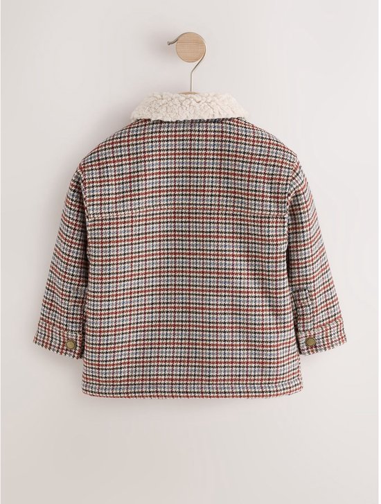 Achterkant van de geruite shacket met borgkraag, hangend aan een hanger.