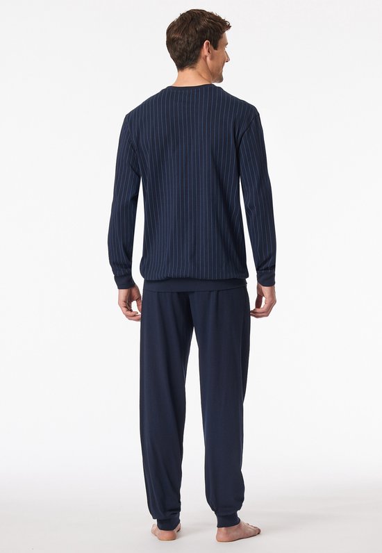 Man van achteren gezien, draagt een donkerblauwe pyjama met verticale strepen en effen donkerblauwe broek.