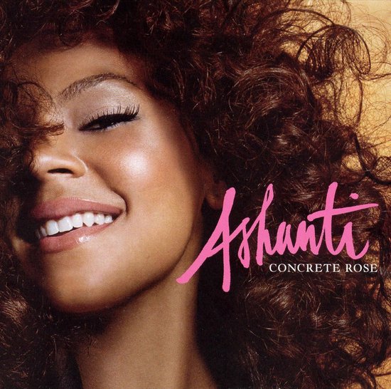Close-up van Ashanti met een grote glimlach en krullend bruin haar, met de tekst 'Ashanti Concrete Rose'.