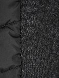 Close-up van de textuur van het gebreide grijze zijpaneel en het zwarte gewatteerde paneel van een bodywarmer.