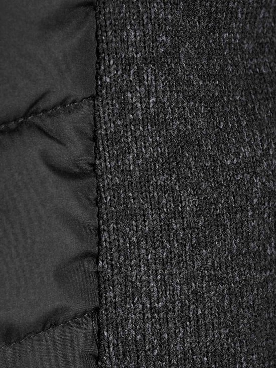 Close-up van de textuur van het gebreide grijze zijpaneel en het zwarte gewatteerde paneel van een bodywarmer.