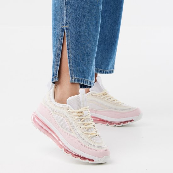 Roze, nude en witte lage sneakers met veters en een doorschijnende roze zool. Gedragen met spijkerbroek.