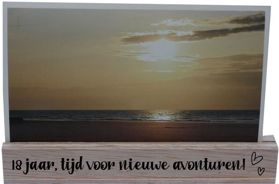 Houten fotostandaard met opdruk "18 jaar, tijd voor nieuwe avonturen!" en een foto van een zonsondergang aan zee.