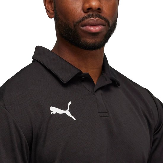 Close-up van een man die een zwarte polo draagt met Puma-logo op de linkerborst.
