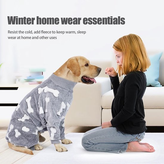 Labrador in grijze pyjama met botjesprint zit voor meisje