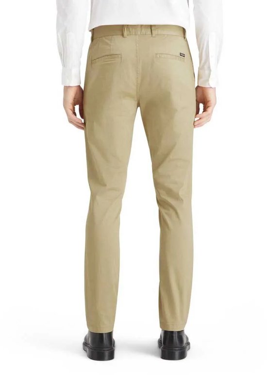 Achterkant van een man in beige chino broek, witte overhemd en zwarte schoenen.