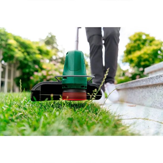 Close-up van de Bosch EasyGrassCut 18V-230 grastrimmer die gras maait.