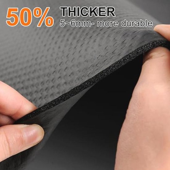 Close-up van een dikke, zwarte fitnessmat die 50% dikker is, met een hand die de textuur ervan laat zien.