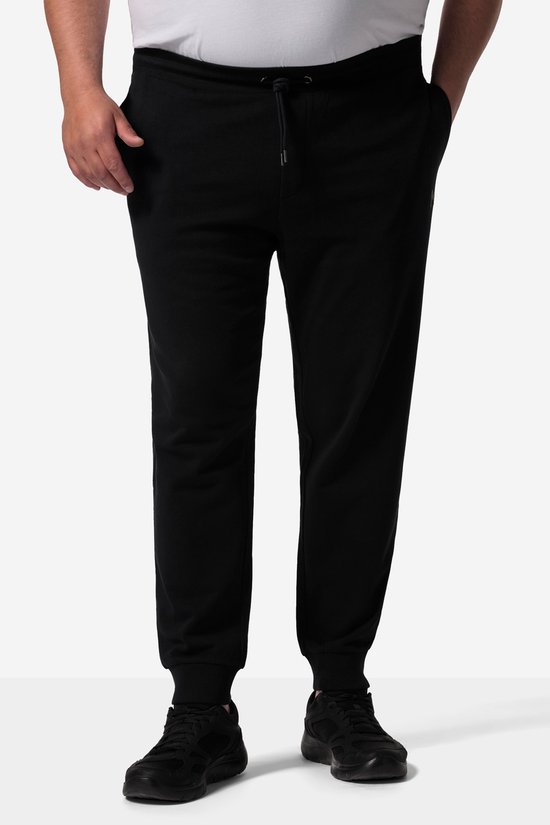 Man met handen in de zakken van een zwarte trainingsbroek met trekkoord aan de taille.