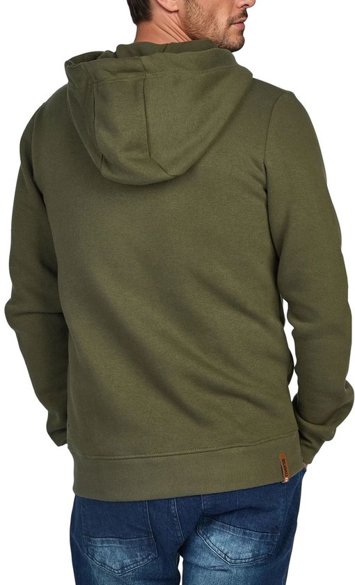 Man met de rug naar ons toe, draagt een olijfgroene hoodie met capuchon en spijkerbroek.