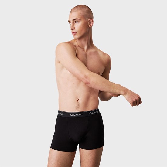 Man met een korte broek in zwart, met Calvin Klein logo op de tailleband.
