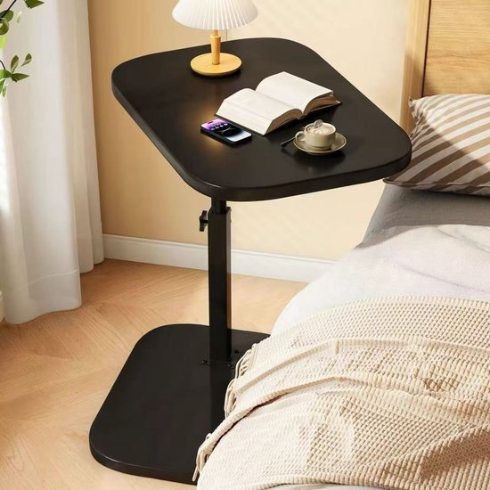 Table d'appoint noire avec lampe, livre et téléphone à côté d'un lit.