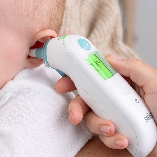 Een hand gebruikt de Braun oorthermometer om de temperatuur van een baby te meten.
