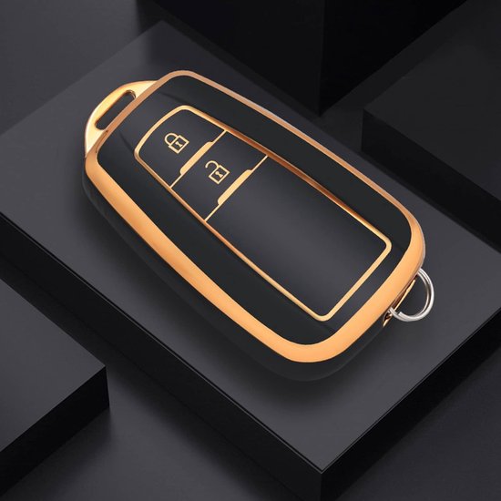 Zwart autosleutelhoesje met gouden rand en knoppen op een donkere achtergrond.