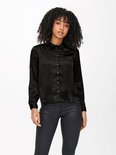 Model met zwarte satijnen blouse, lange mouwen en zwarte broek.