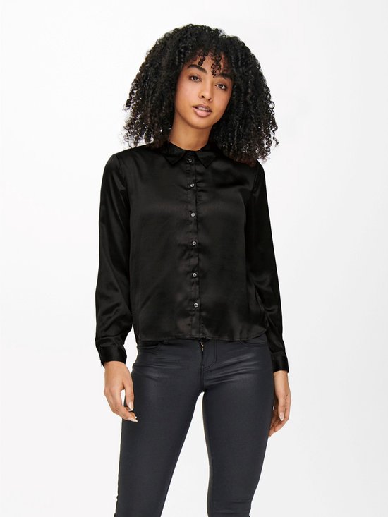 Model met zwarte satijnen blouse, lange mouwen en zwarte broek.