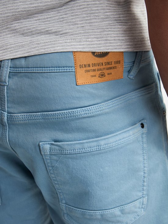 Detail van de achterkant van een lichtblauwe denim short met een leren Petrol Industries-label.