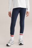 Meisje in donkerblauwe legging en witte sokken met rode strepen.