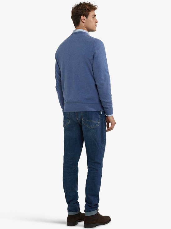 Achteraanzicht van man in blauwe McGregor V-hals trui, spijkerbroek en bruine schoenen.