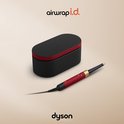 Dyson Airwrap i.d. multistyler in rood fluweel met goud, naast de bijpassende opbergdoos.